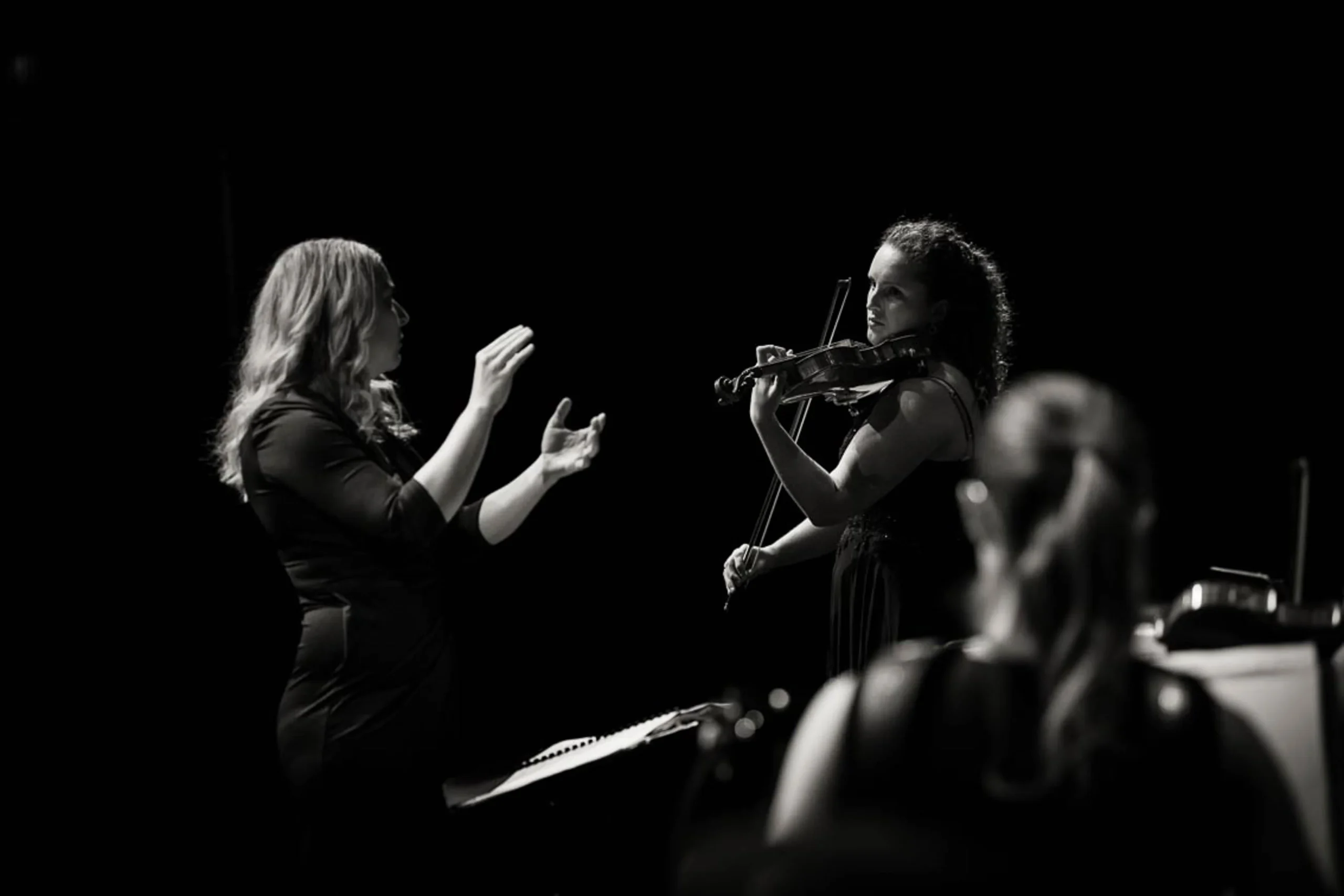 Dirigentka vodi violinistko med skupnim nastopom na koncertnem odru.