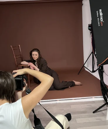 vani-foto-dinamicno-fotografiranje-na-tleh Vani v akciji fotografira stranko iz nizkega kota na rjavem studijskem ozadju.